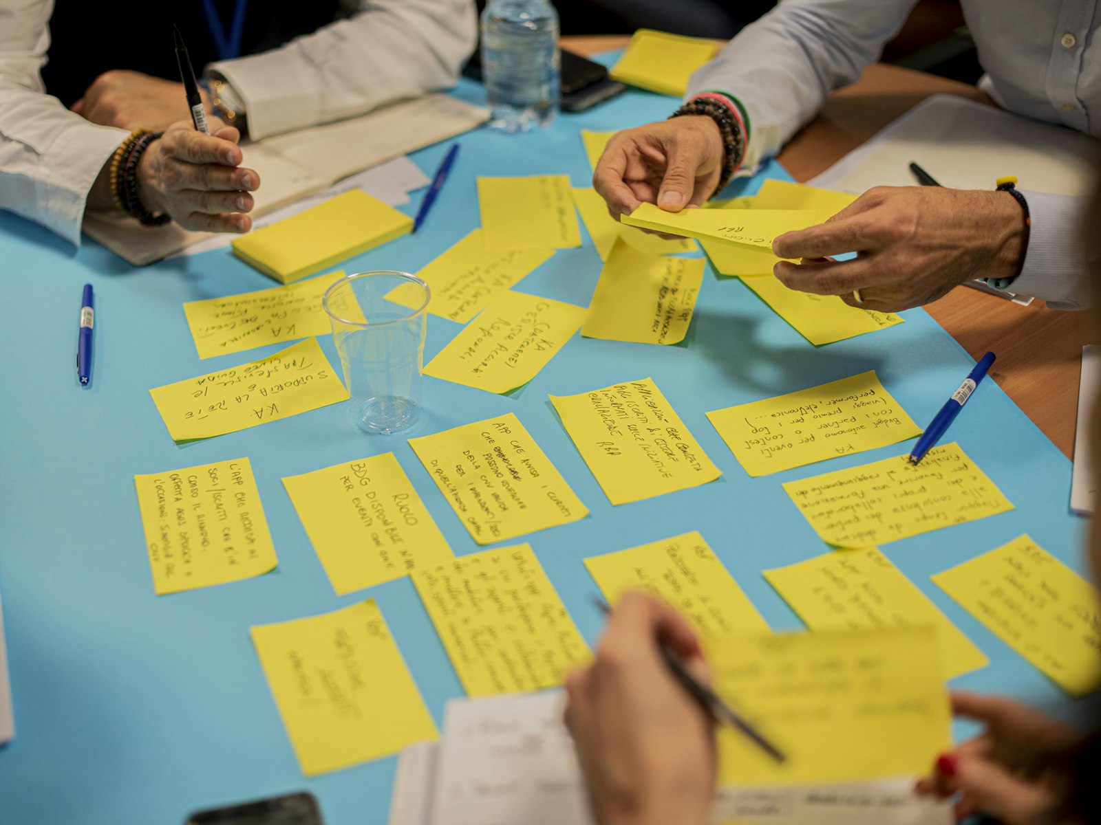 Several hands arranging sticky notes on a table