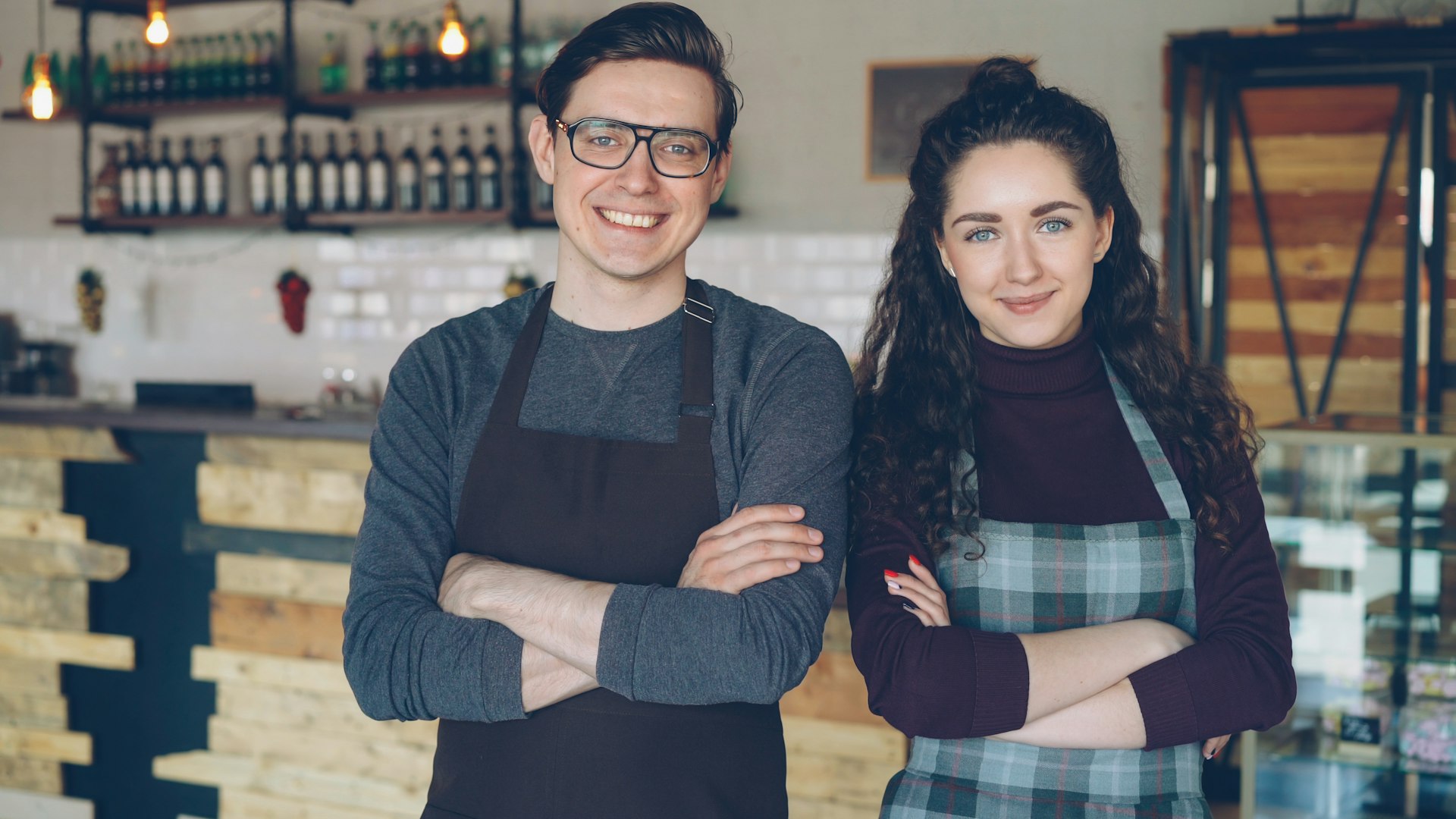 Dos dueños de un café, de pie y sonrientes en su local