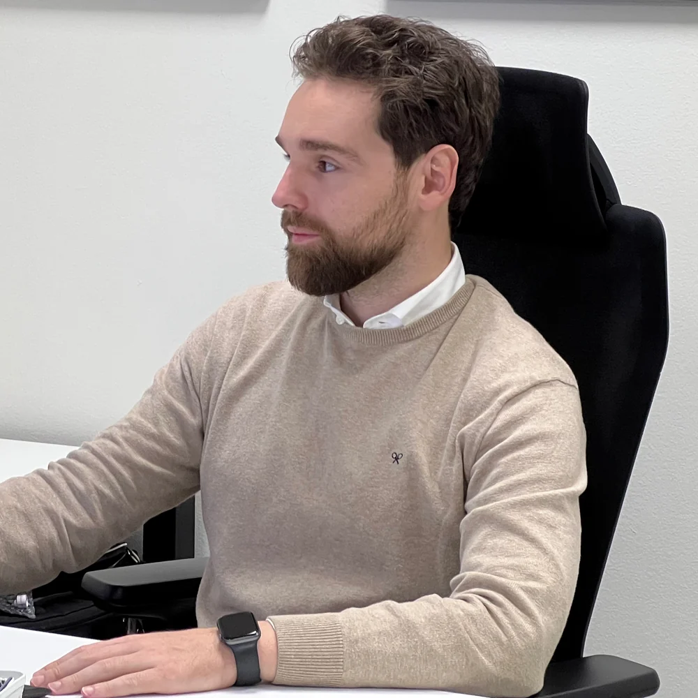 Carlos Pascual Adell, fundador de The Beacon Holding, de perfil y con jersey beige, sentado en su puesto de trabajo ante el escritorio